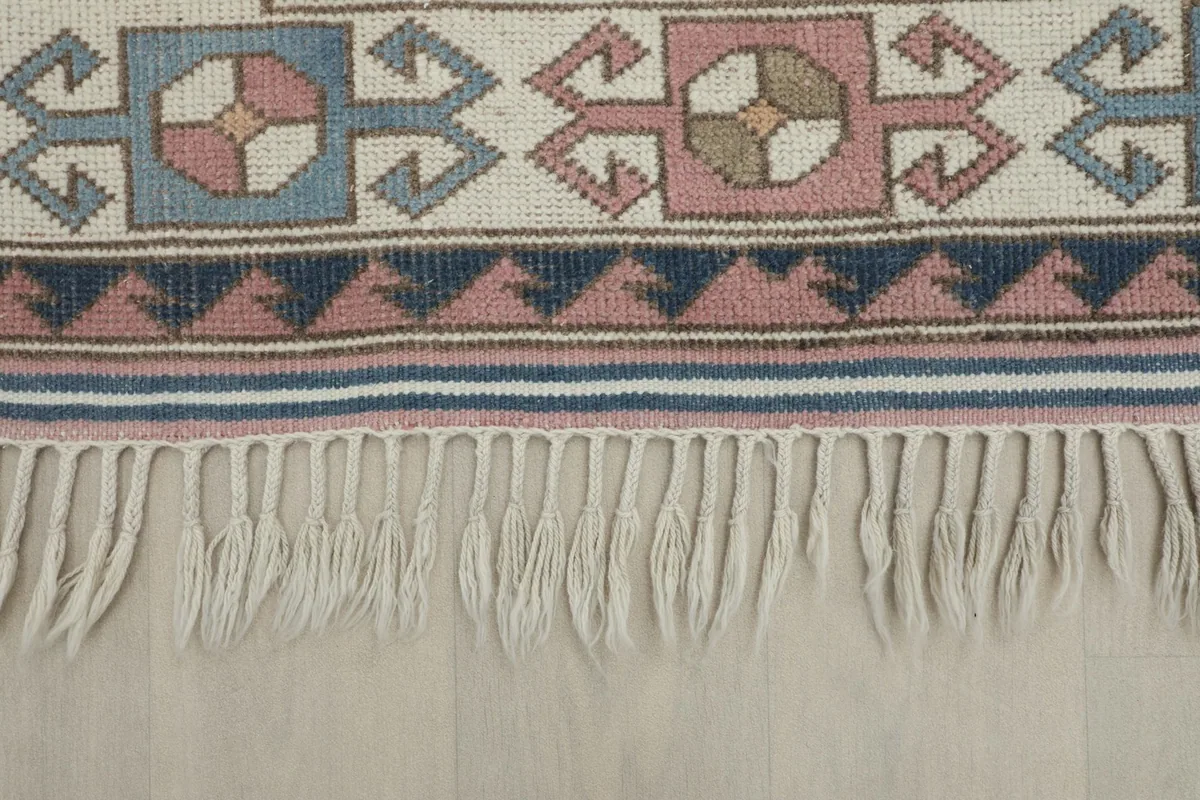 Close-up view of the white fringe and the detailed border patterns of the Anatolian rug