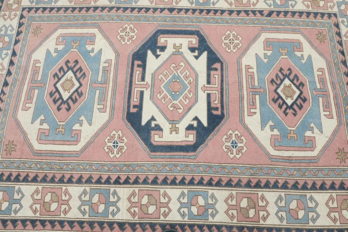 Overhead view of the central motifs and surrounding patterns of the pink and blue Anatolian rug