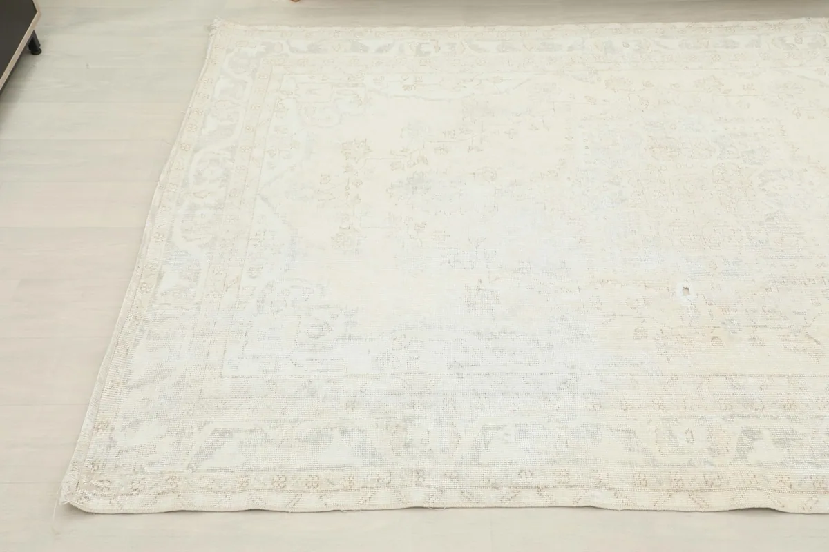 Another corner view of the vintage rug, showing the overall faded appearance and pattern details.