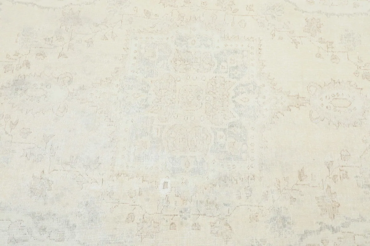 Detailed view of the rug's center, revealing the subtle cream, gray, and beige colors and motifs.