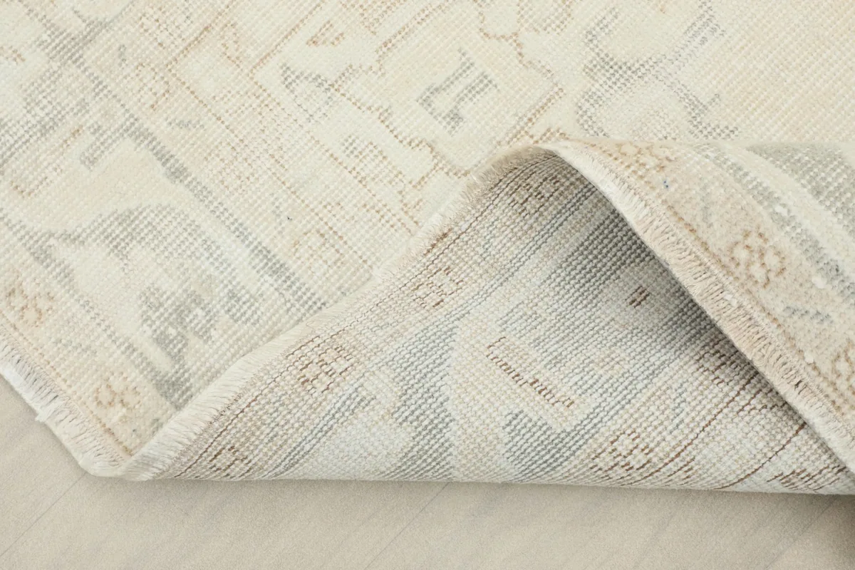 Folded corner of the rug showing the hand-knotted cotton foundation and wool pile reverse.