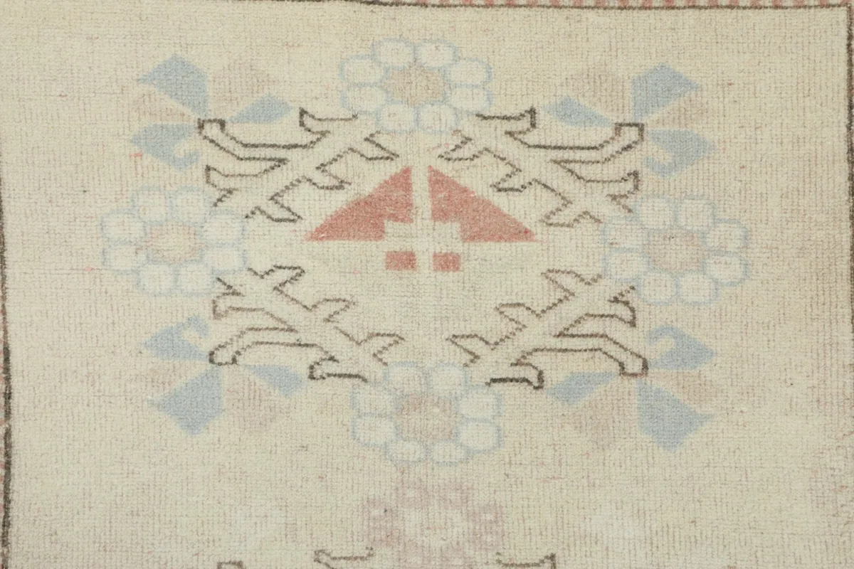 Close-up of a specific tribal motif in rose, blue, and ivory on the rug