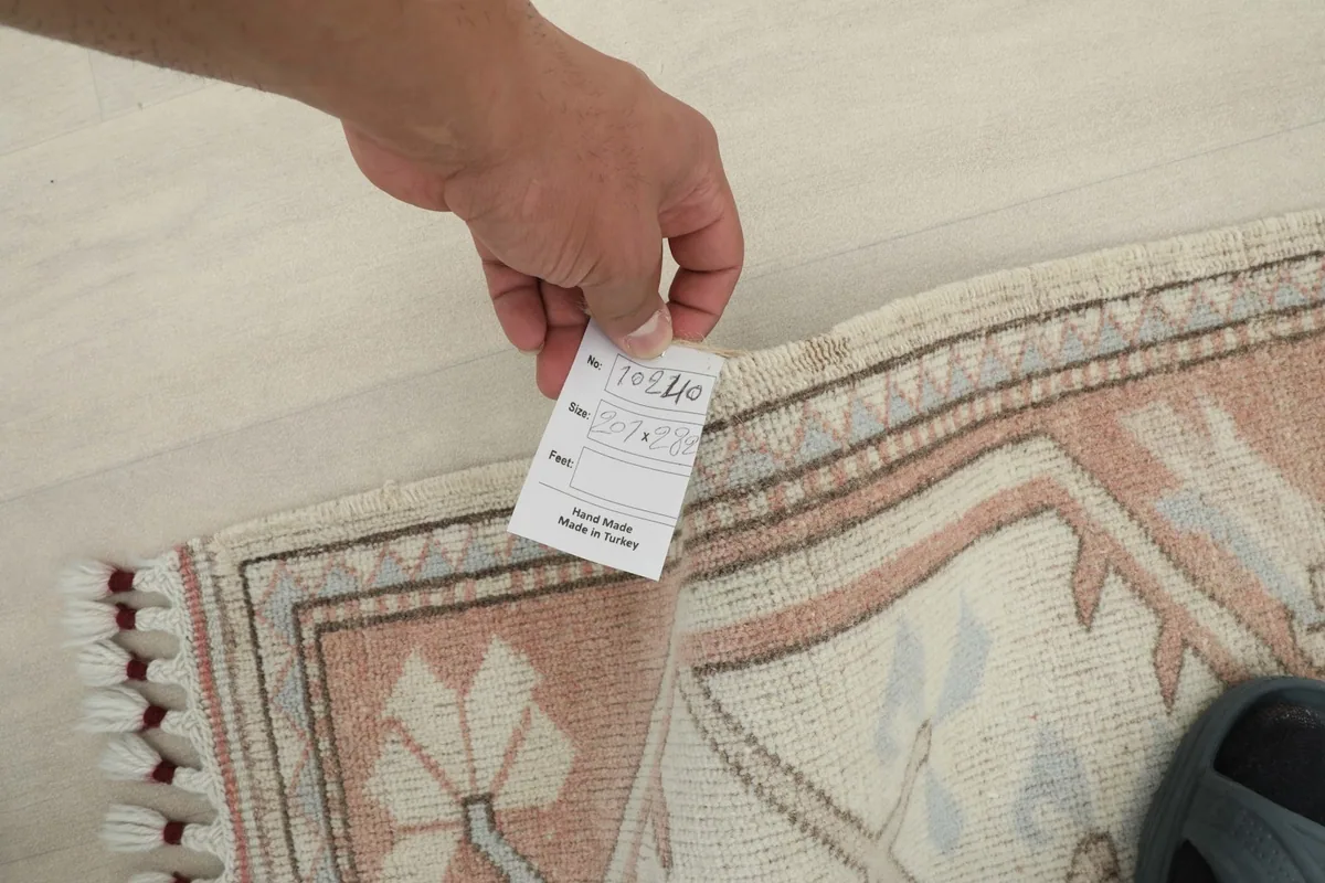 Hand holding a tag near the rug's edge, showing craftsmanship