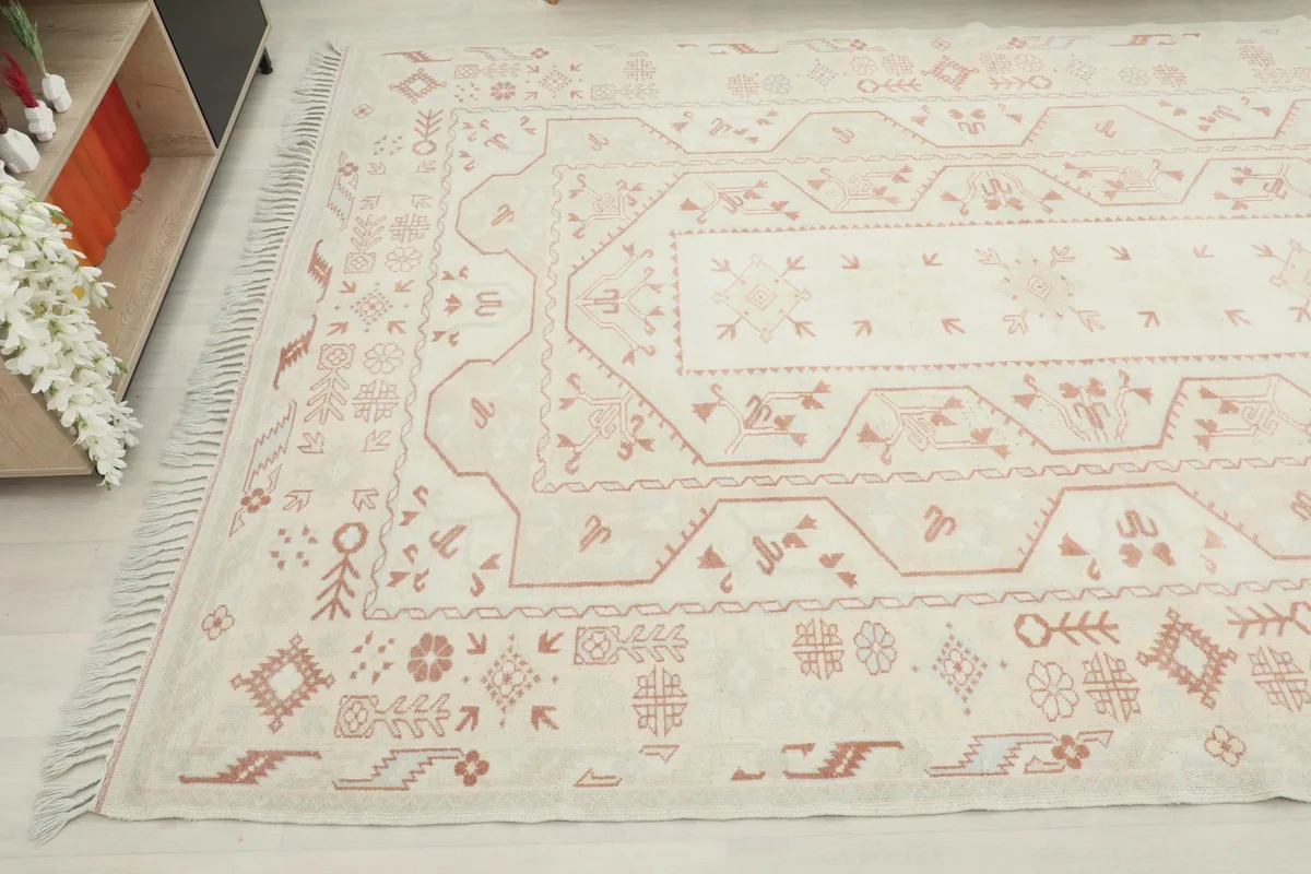 Angled view of the rug's surface, capturing the intricate rust motifs on a cream background