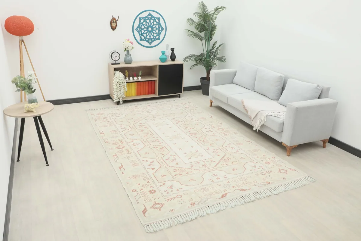 Large cream and rust area rug in a modern living room setting with a light gray sofa