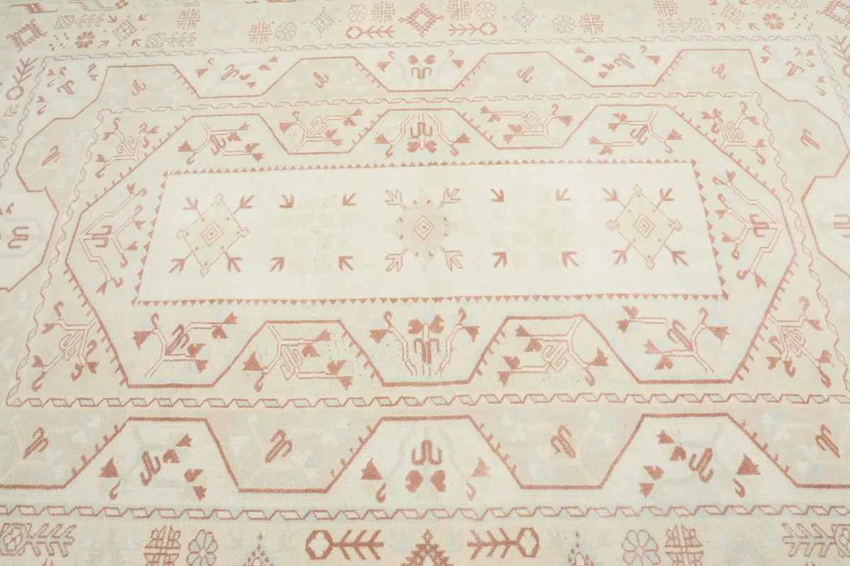 Close-up detail of the central medallion and surrounding geometric patterns in rust on cream