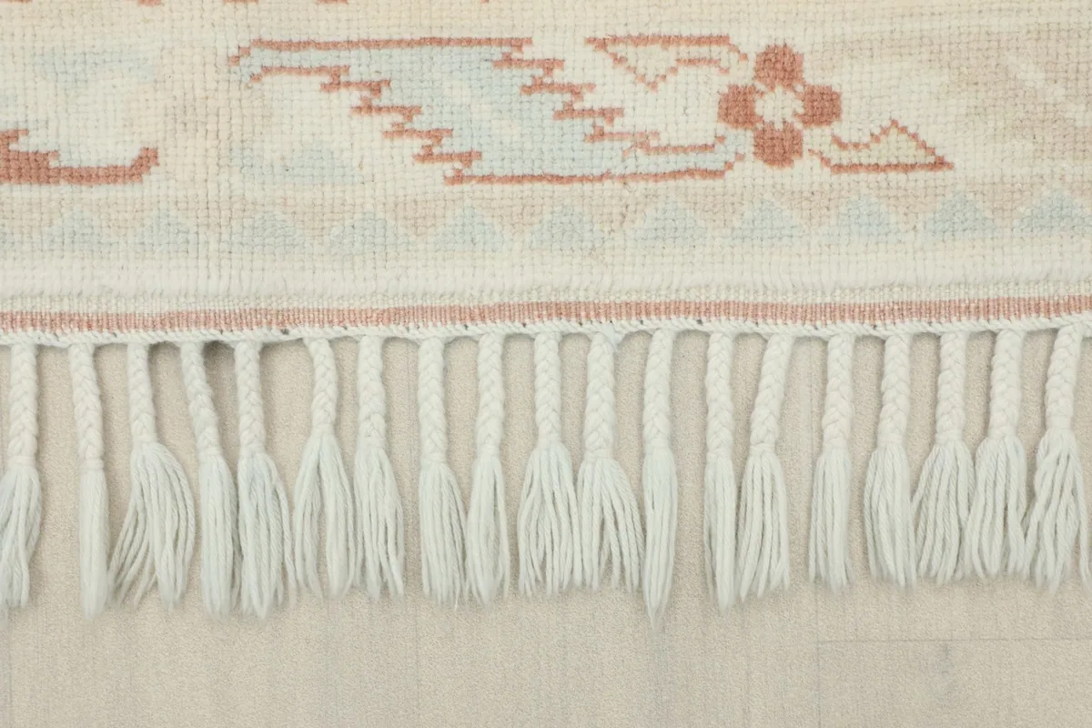 Close-up of the braided fringe along the edge of the vintage hand-knotted rug