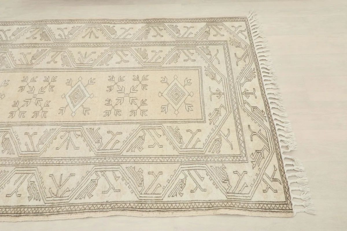 Close-up of the rug's corner showcasing the beige field and gray border