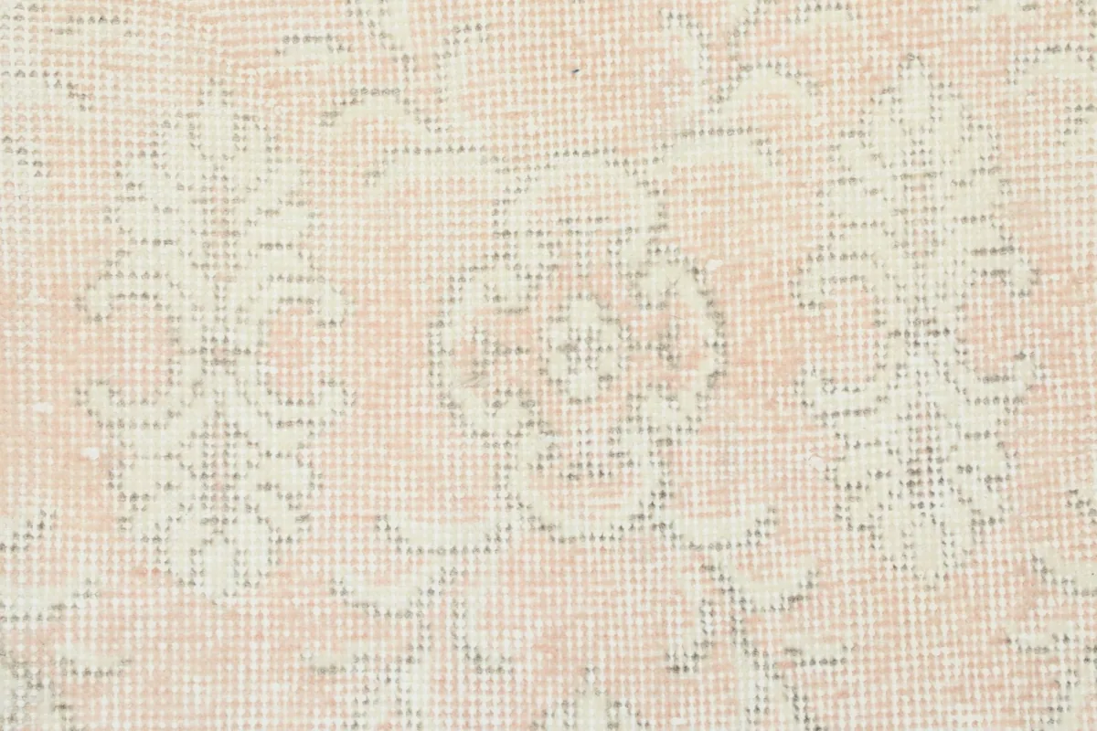 Detailed close-up of a floral motif and the texture of the faded wool pile.