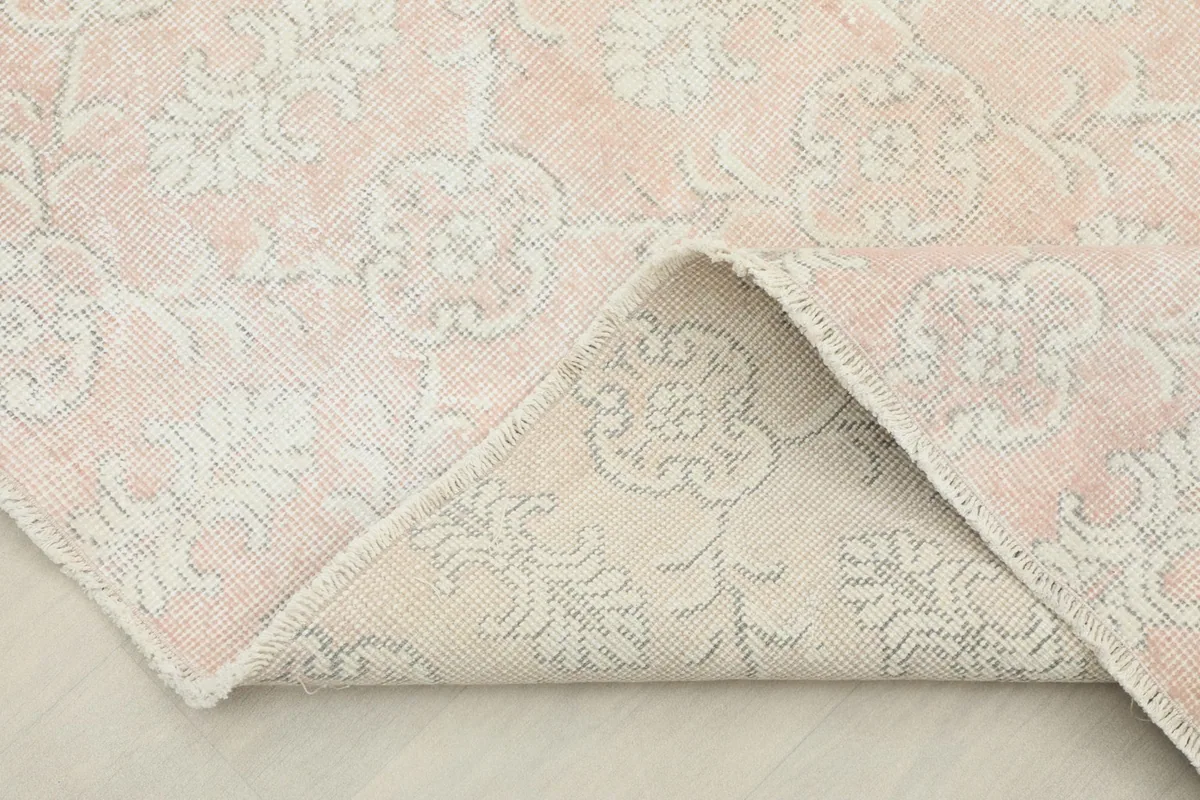 Corner folded back to reveal the hand-knotted cotton foundation and reverse side of the rug.
