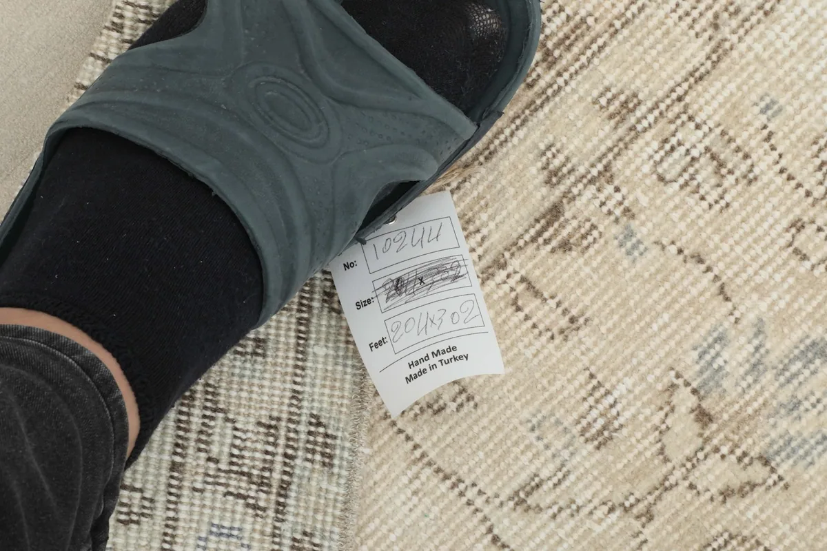 Foot next to the rug's label, showing 'Hand Made in Turkey' and material