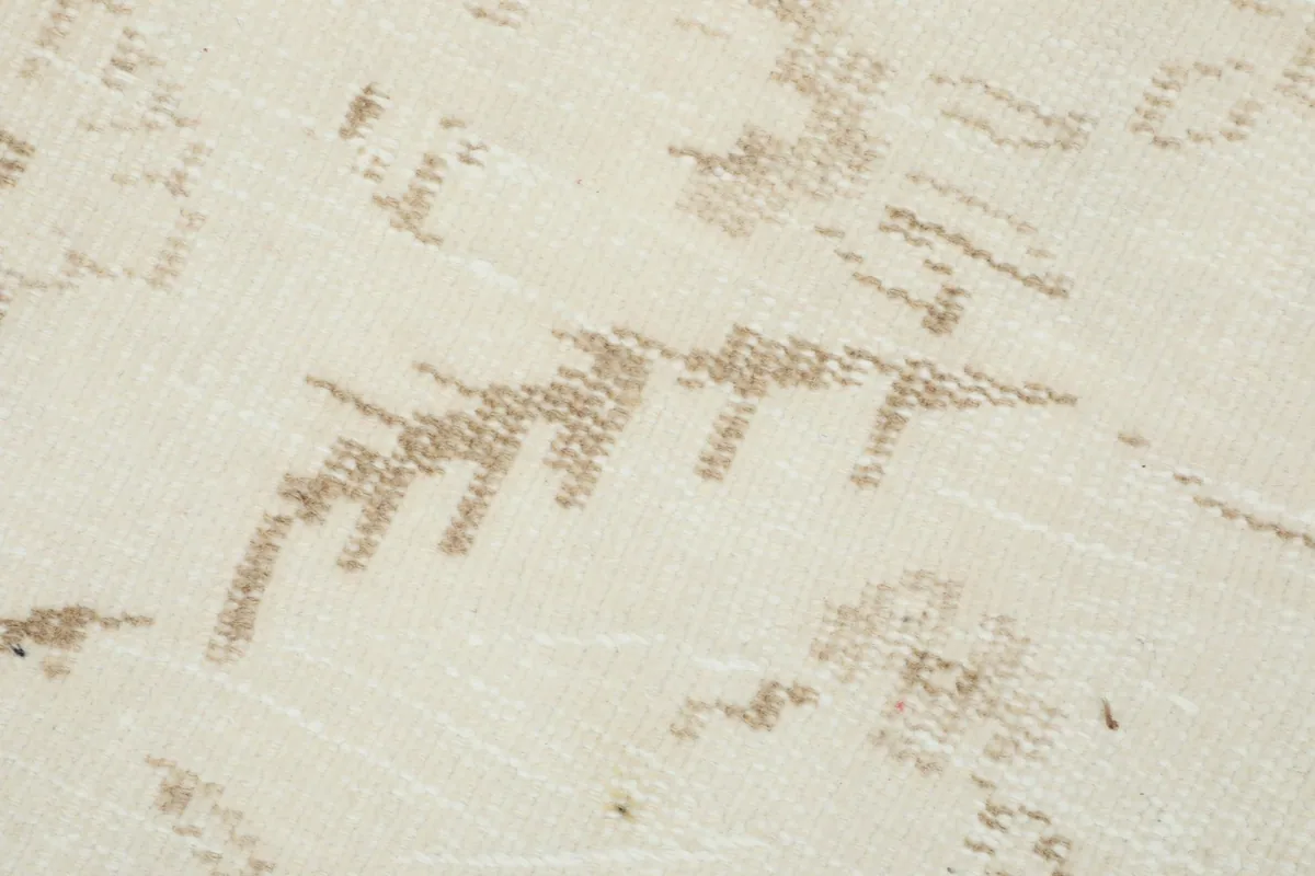 Extreme close-up of the rug's low wool pile and the hand-knotted texture, revealing slight variations in color.