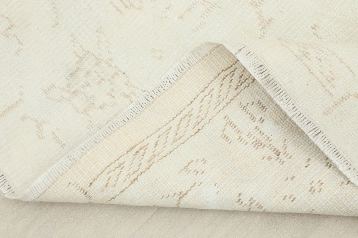 View of the rug's underside, showing the cotton foundation and the tightly woven hand-knotted construction.
