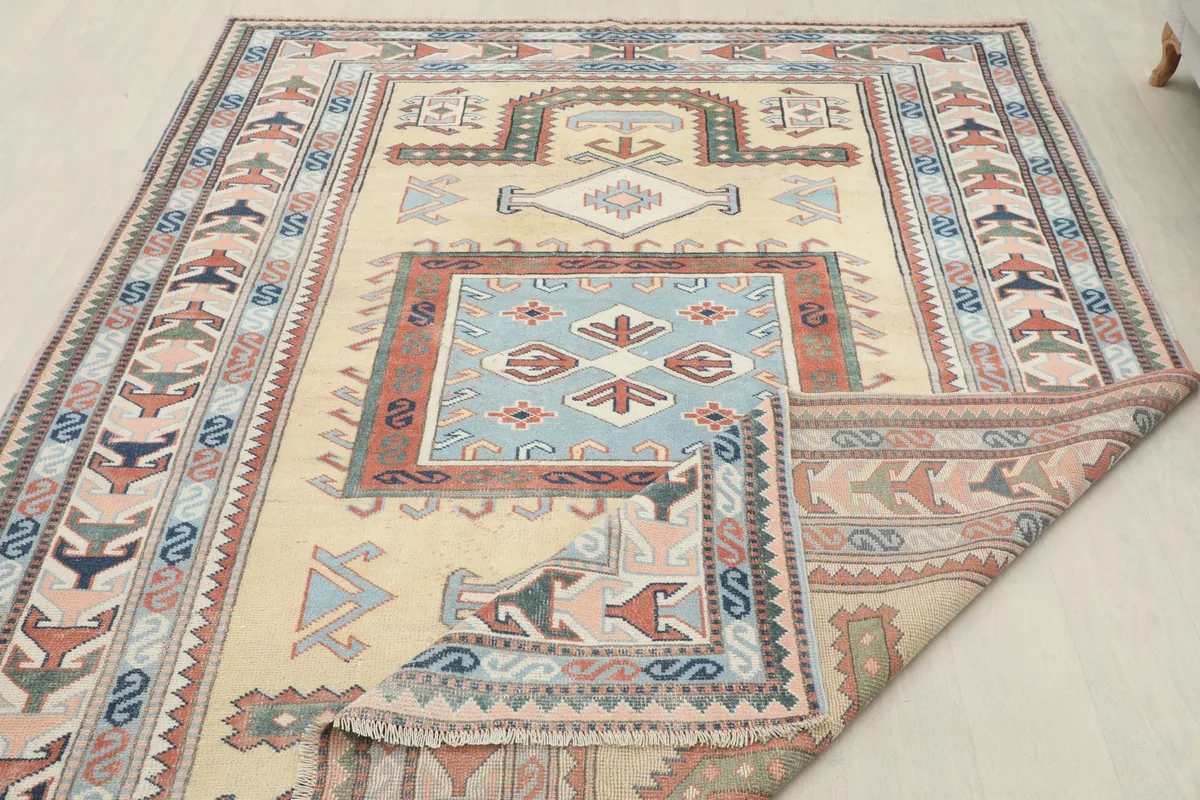 The rug partially folded to show its flexibility and the detailed patterns along the edges.