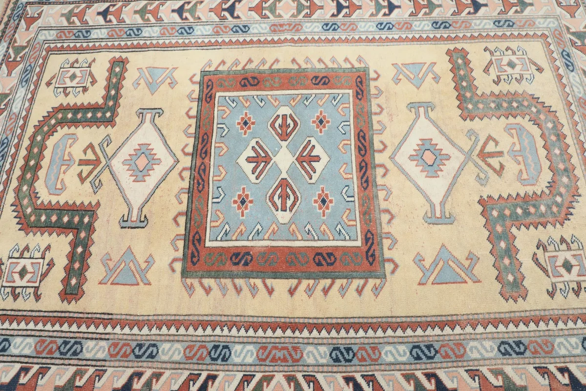 Overhead close-up of the rug's central design, featuring a square blue medallion surrounded by a beige field.