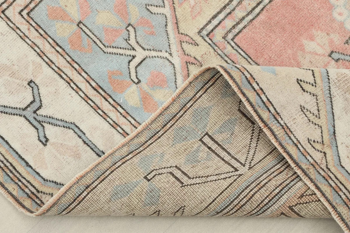 View of the rug's back and a folded corner, showing the cotton foundation and knotting
