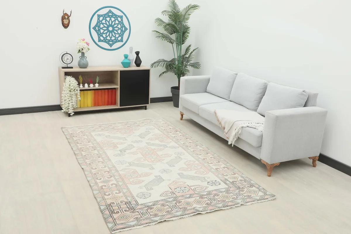 Ivory and rose vintage Anatolian rug displayed in a living room setting with a light gray sofa