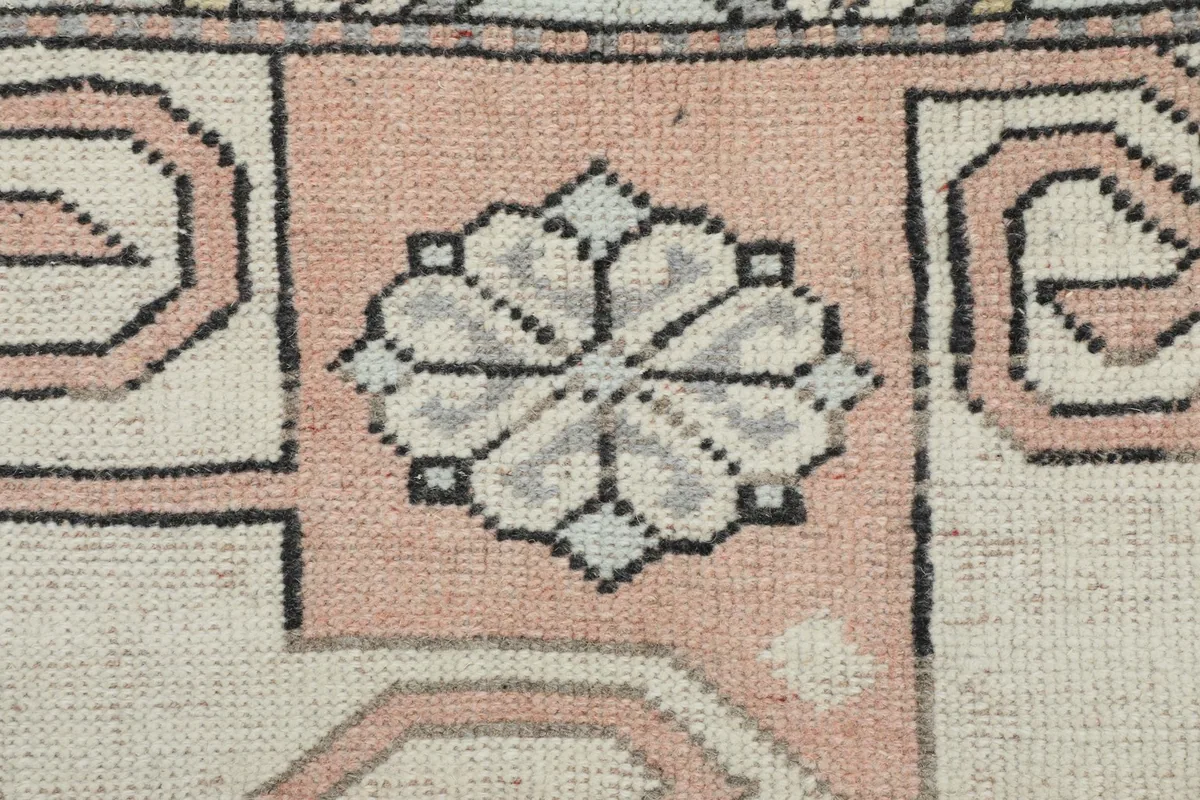 Macro detail of a rose and gray floral-like motif within the rug's pattern