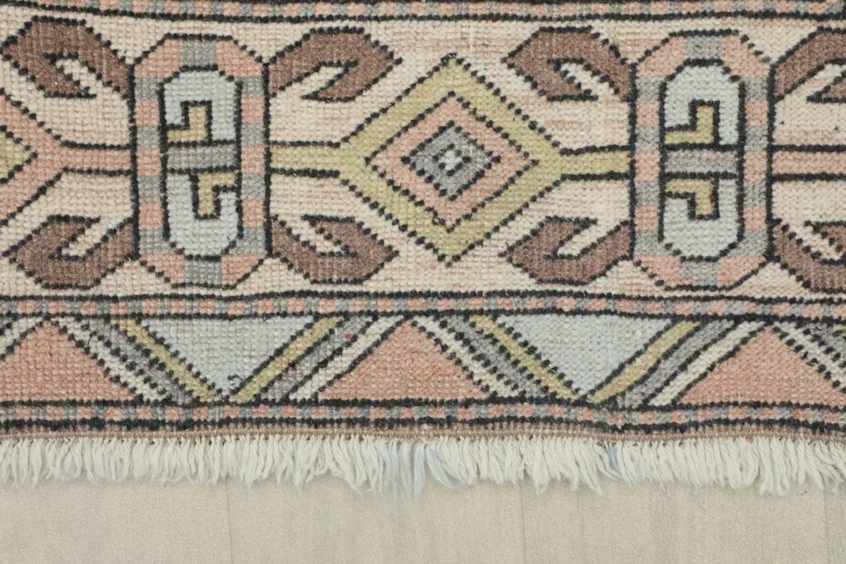 Close-up of the rug's border with various geometric elements and short fringe