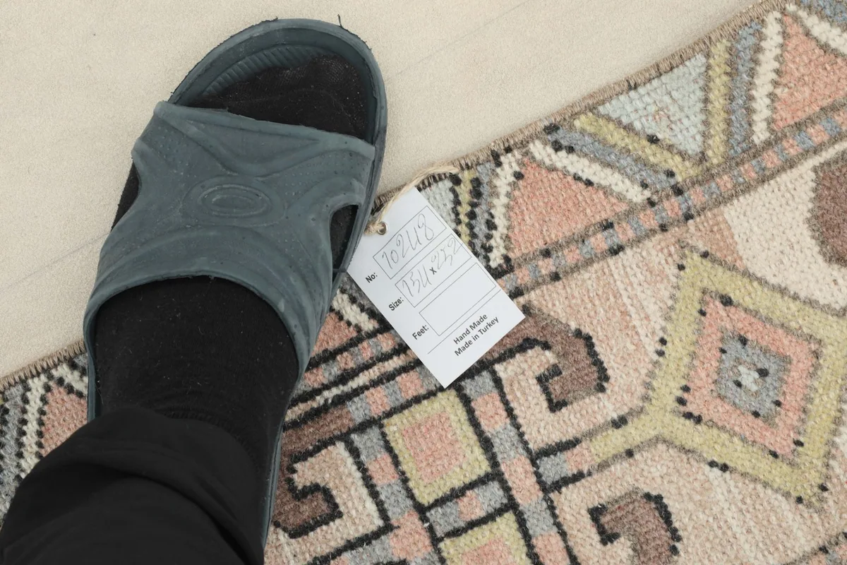 Foot in a slipper placed next to the rug to indicate scale and show texture