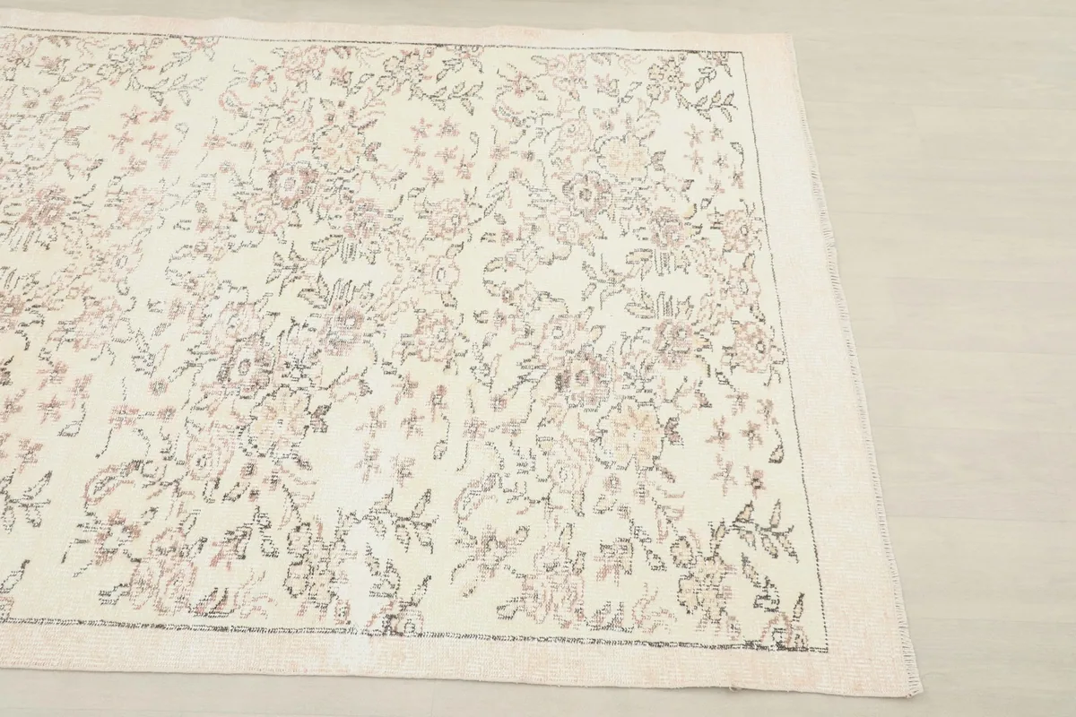 Close-up corner view of the rug, highlighting the subtle border and floral design on the ivory background