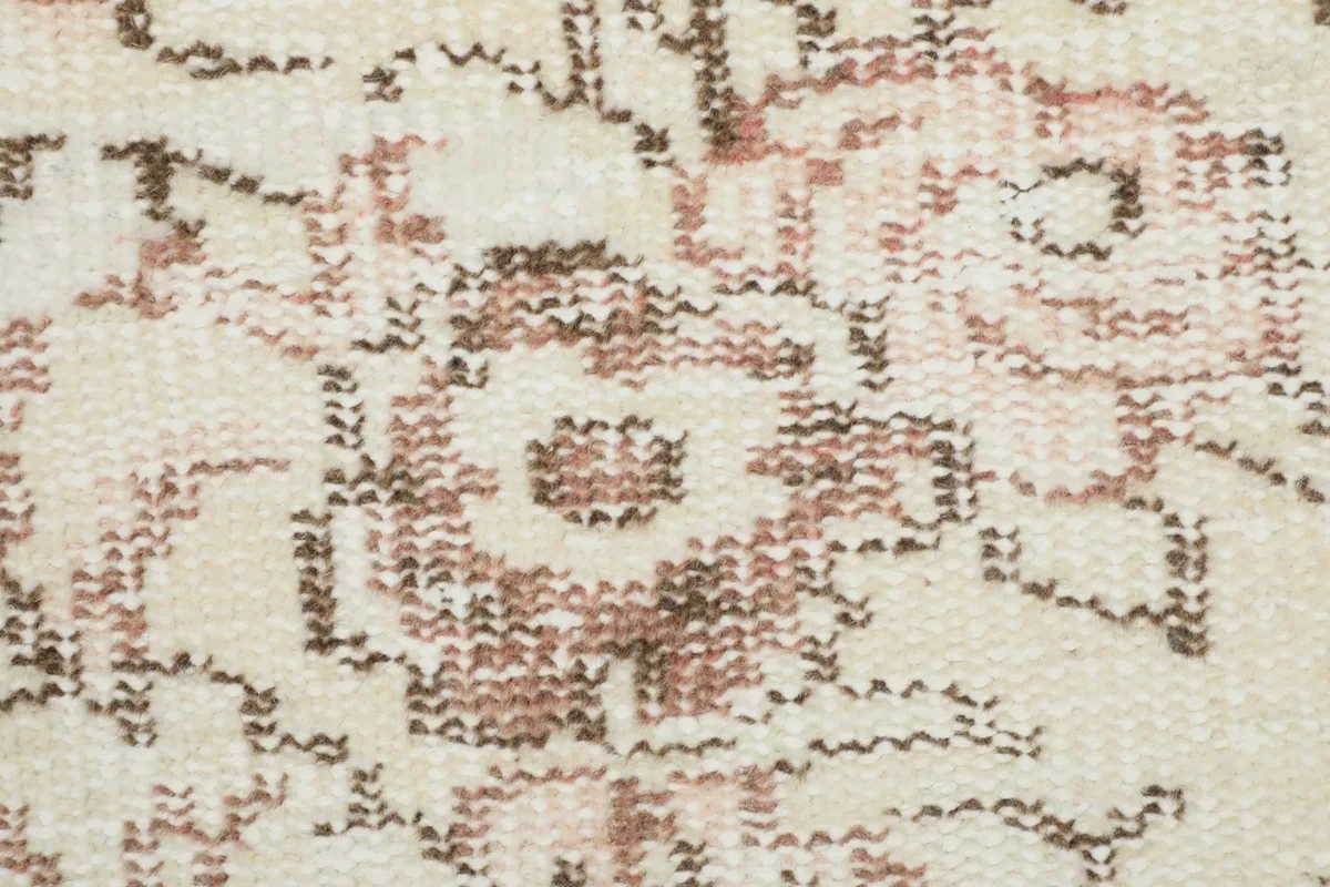 Close-up of the rug's low wool pile, revealing the hand-knotted texture and distressed floral design