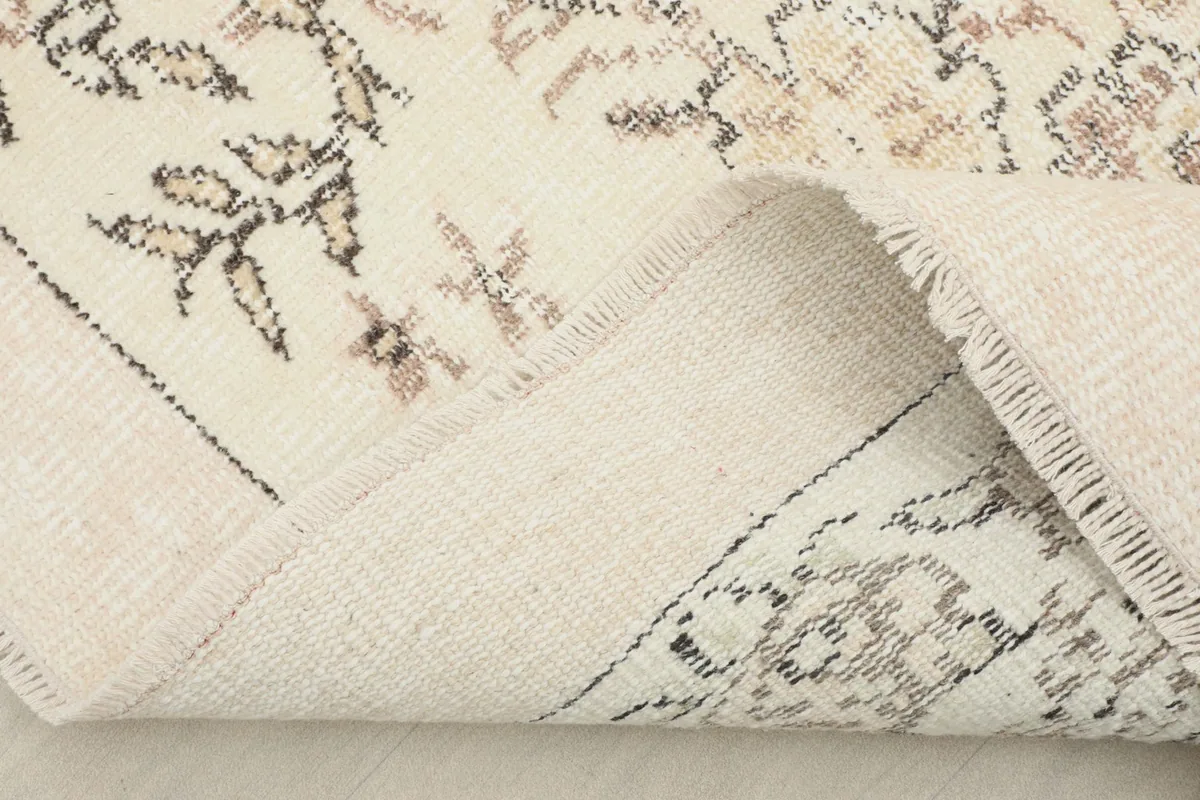 Folded corner of the rug showing the reverse side and the cotton foundation beneath the wool pile