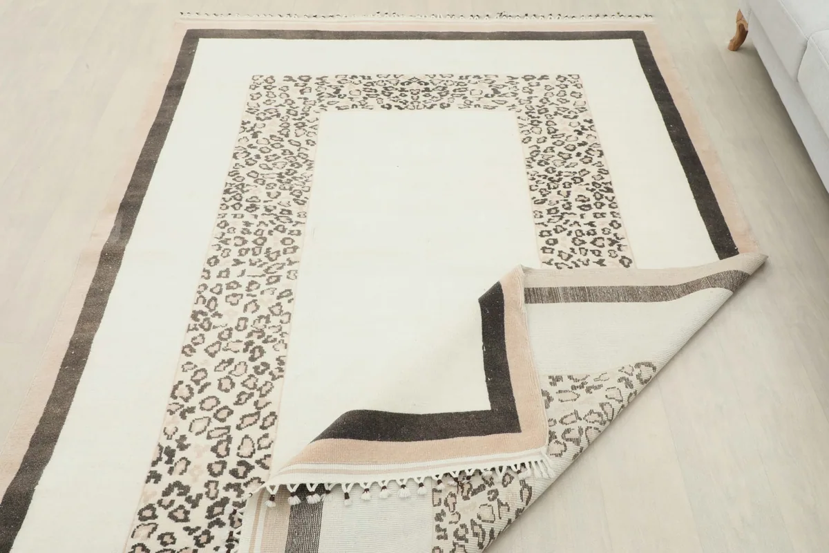 Rug laid out in a room, with one corner folded back to show the underside.