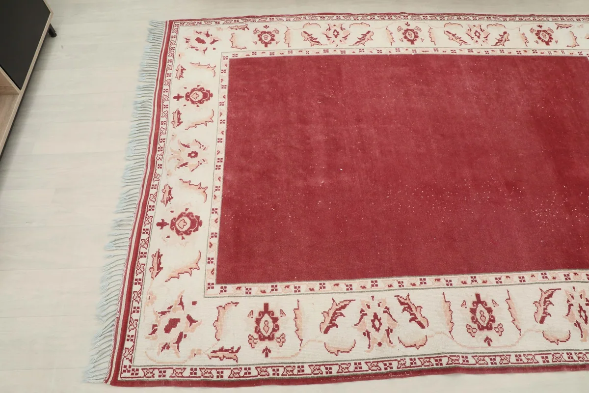 Angled shot highlighting the rug's texture and the detailed floral patterns on the ivory border.