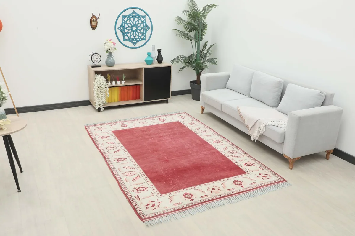 Red and ivory vintage rug in a living room setting with a light gray sofa and wooden console.