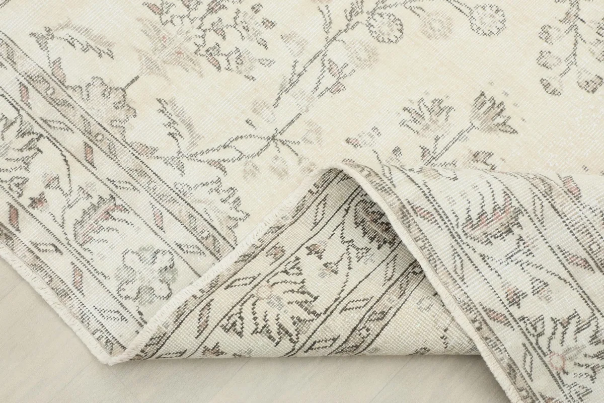 Corner of the rug folded to reveal the thickness and the back of the hand-knotted wool pile.