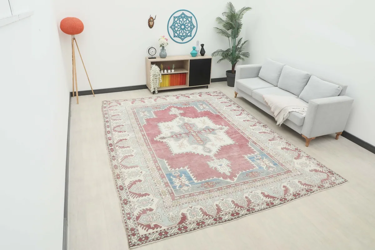 Vintage red and blue area rug displayed in a bright living room setting with a light gray sofa.