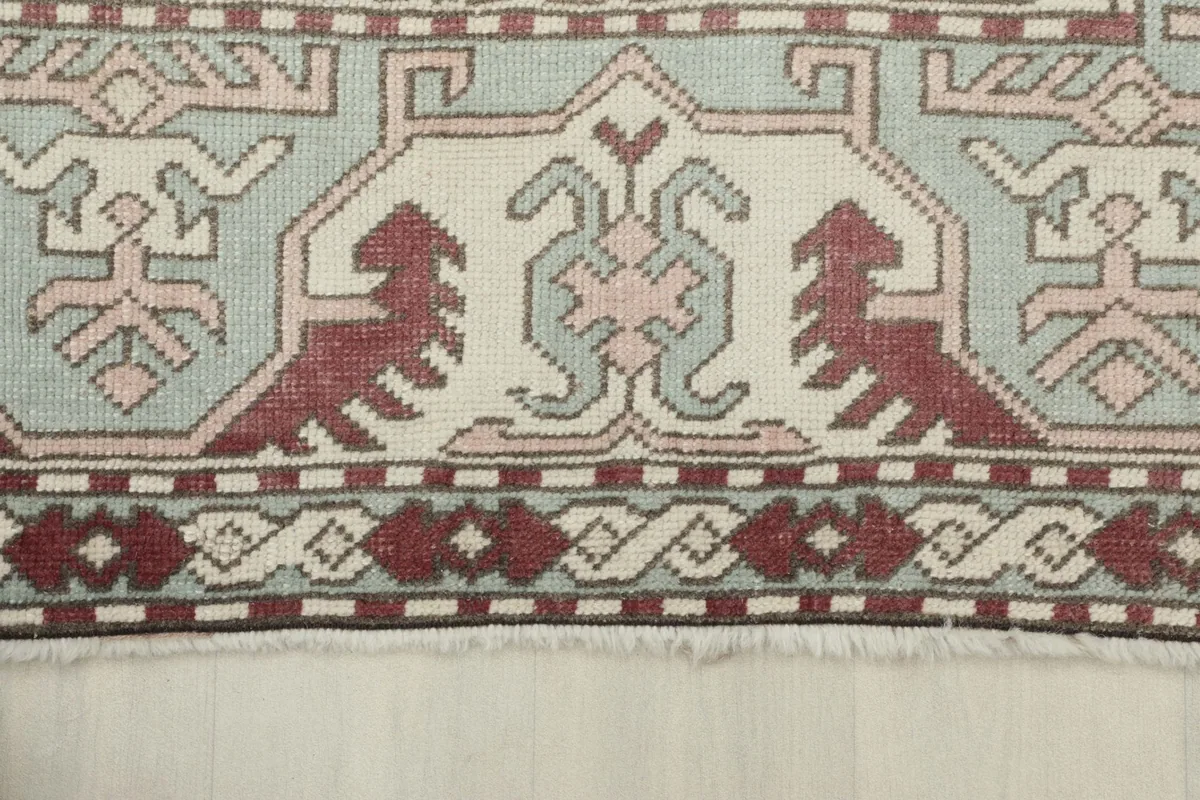 Close-up of the rug's fringe and a section of the border, showing the hand-knotted wool texture.