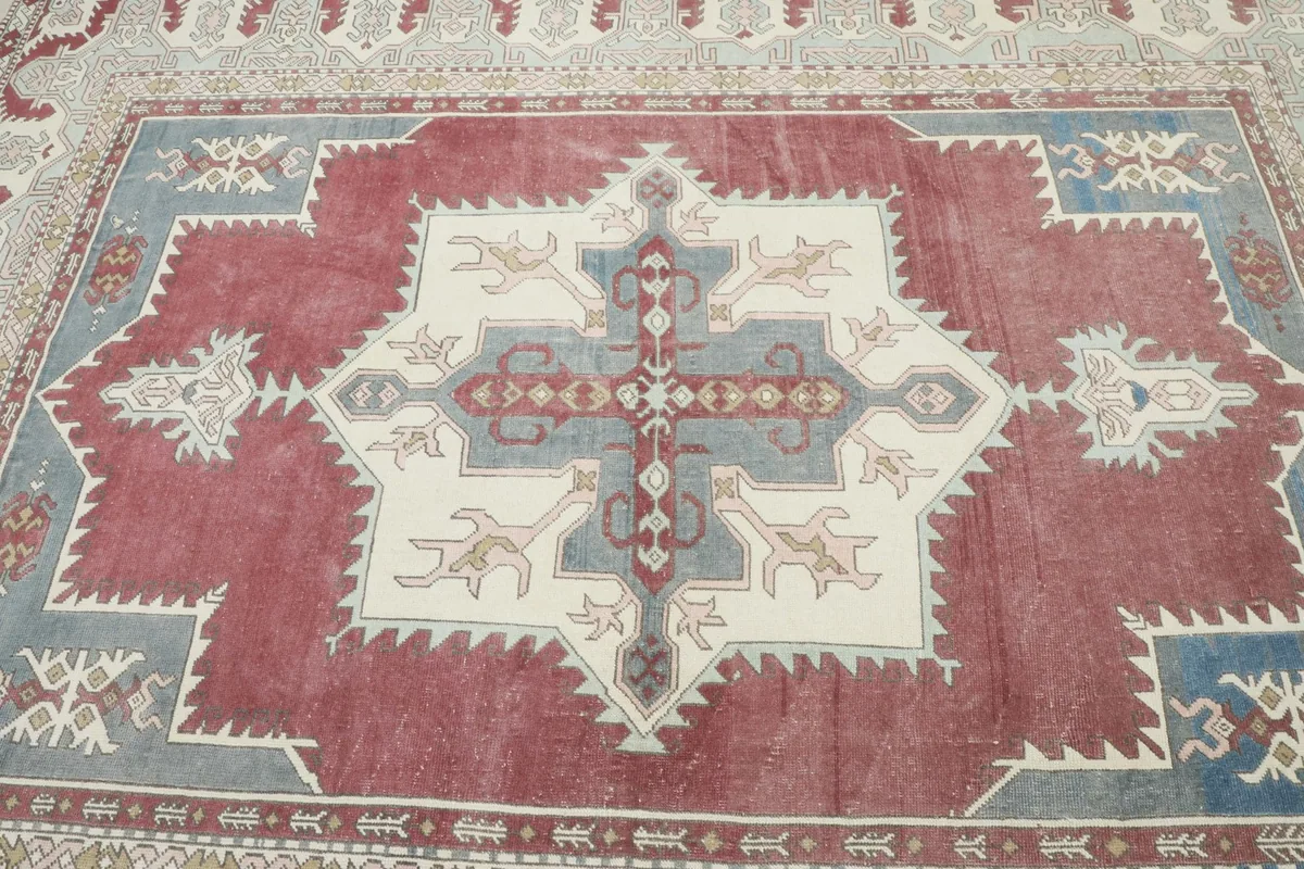 Close overhead view of the rug's central medallion, showcasing the red, blue, and ivory colors and tribal motifs.
