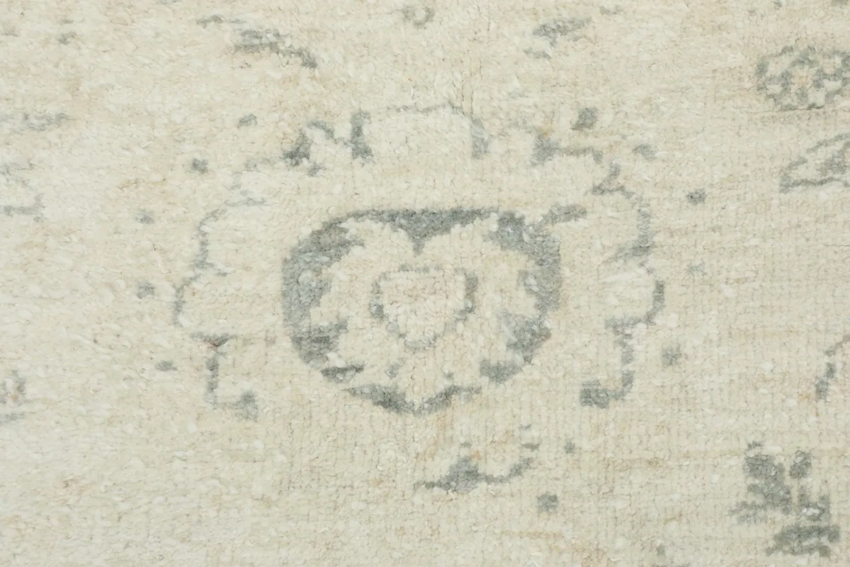 Detailed close-up of a faded gray medallion motif on the ivory field of the vintage rug