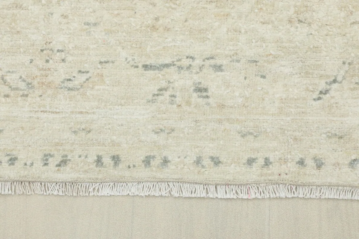 Close-up of the rug's short, natural ivory fringe and the edge of the faded border design