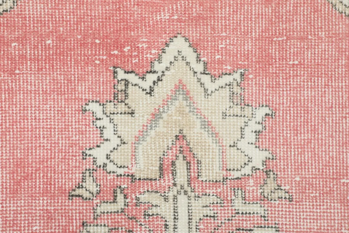 Close-up detail of a motif within the rug's pink field, showing the hand-knotted wool texture