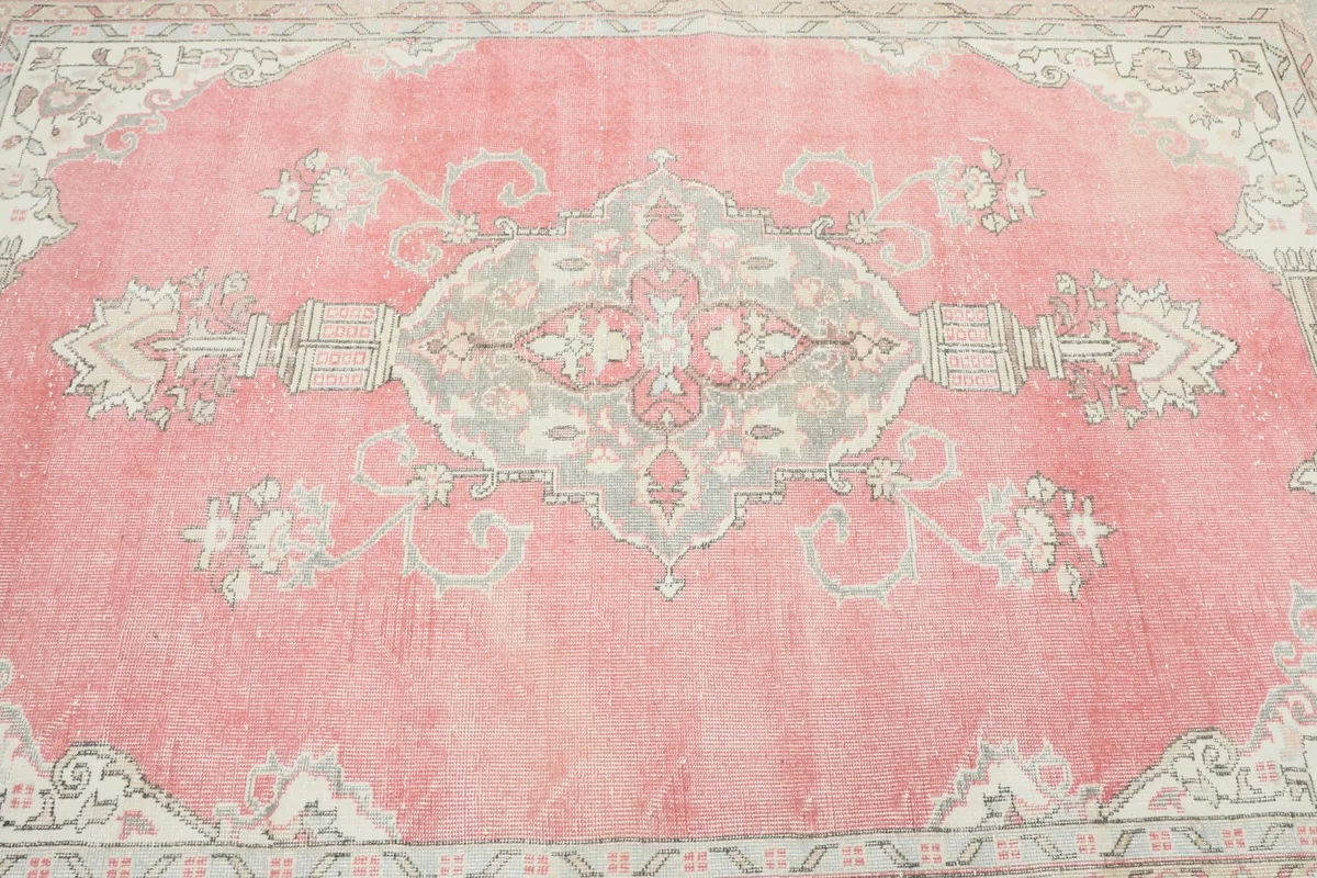 Overhead view of the rug's central pink field and the prominent gray and beige medallion design