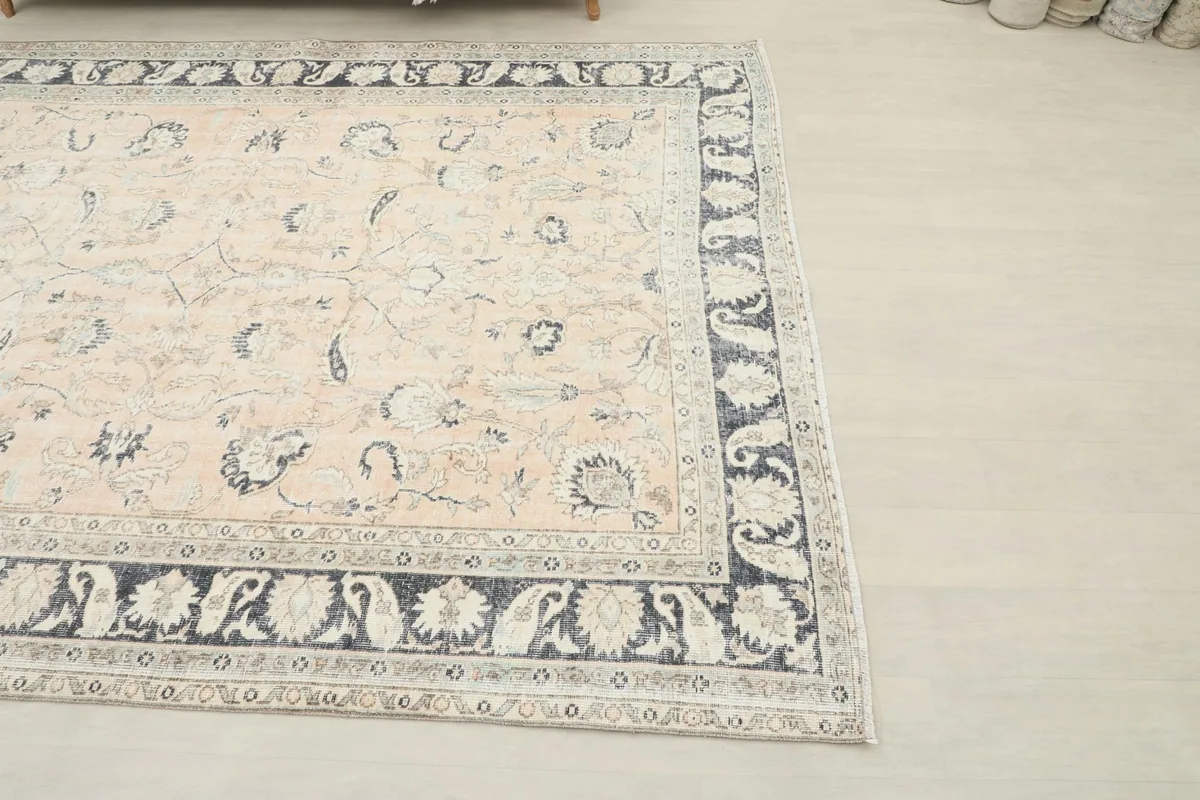 Corner view of the hand-knotted rug, highlighting the charcoal border and rose field.