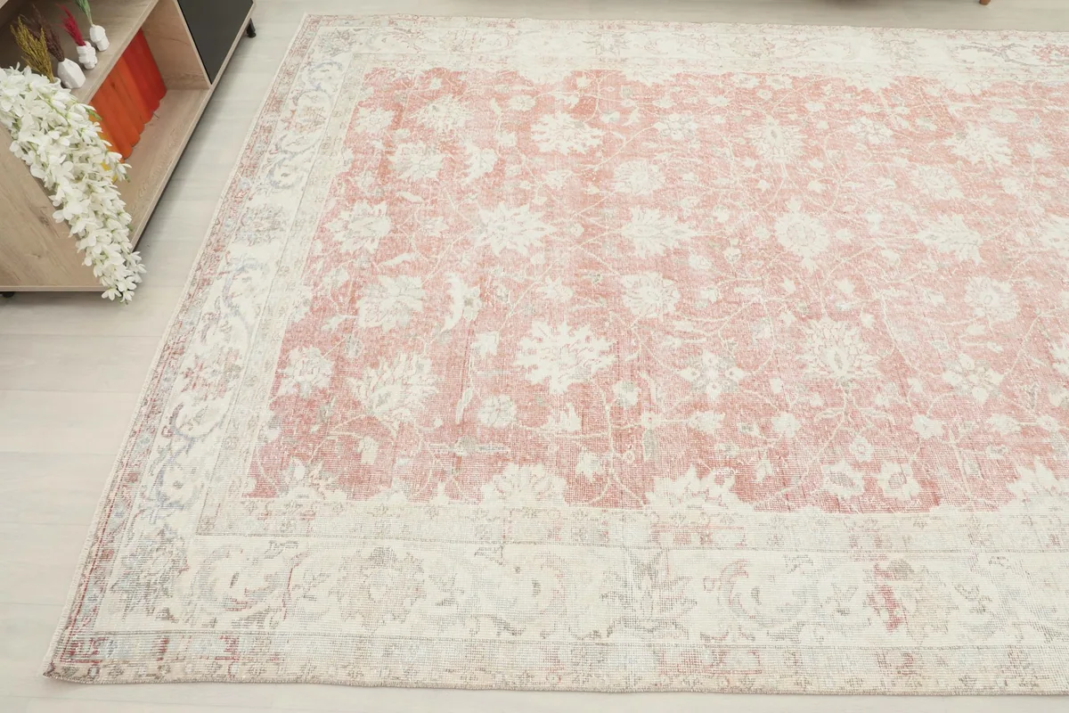 Angled view showcasing the rug's ivory border with detailed floral patterns