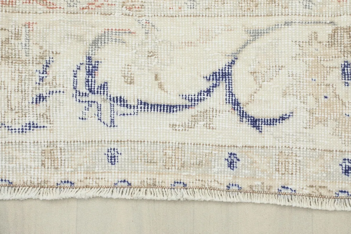 Detail of the rug's border with blue and beige patterns and the short fringe