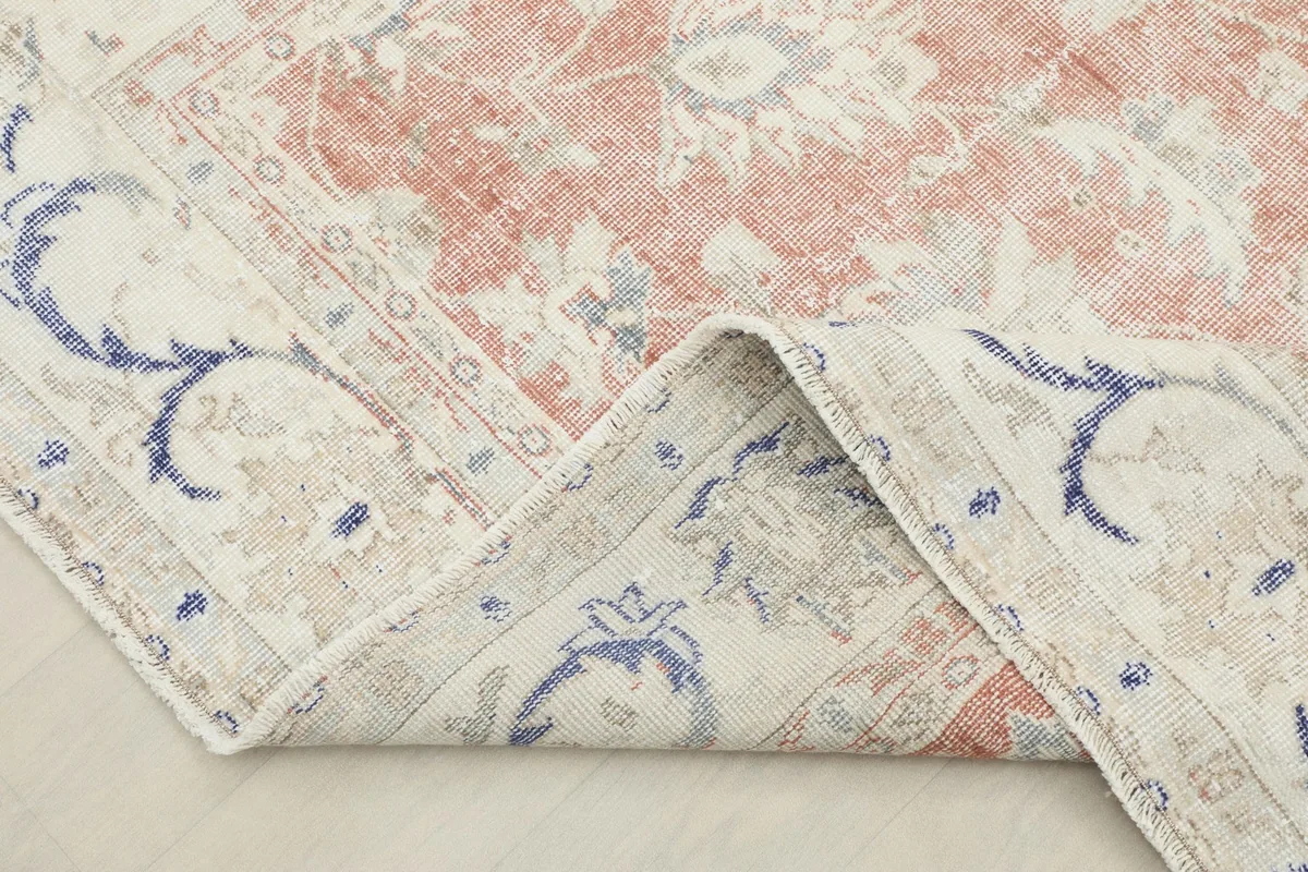 Corner of the vintage rug folded back, revealing the cotton foundation and reverse side