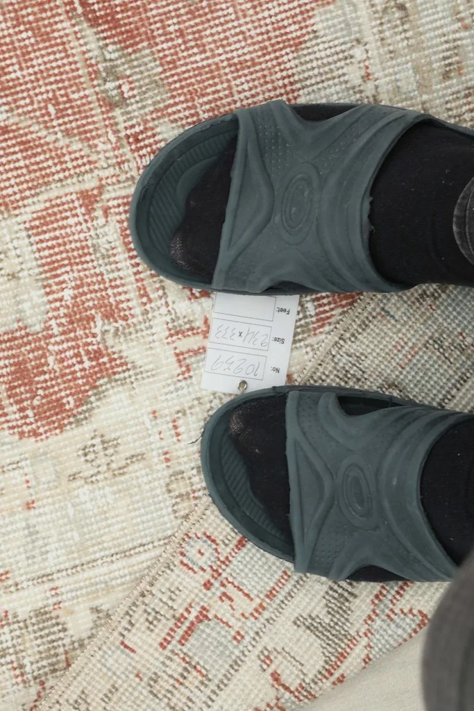 Feet in sandals on the rug, showing scale and the texture of the low pile