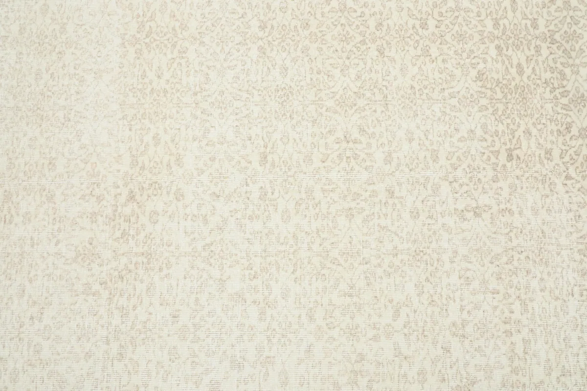 Close-up detail of the faded floral pattern across the cream field of the rug.
