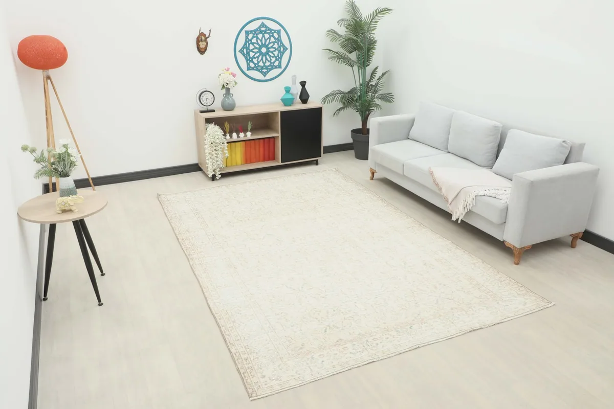 Ivory vintage rug displayed in a living room setting with a light gray sofa and wooden furniture