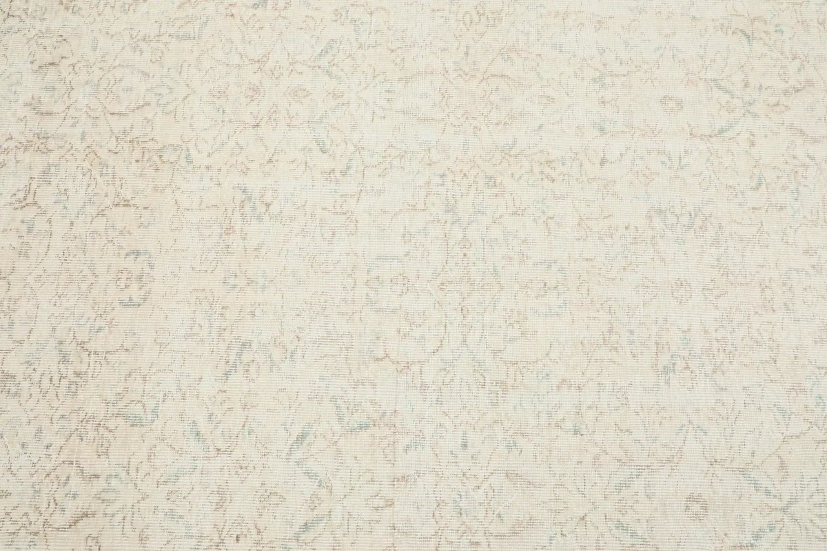 Close-up detail of the rug's central field, revealing the subtle floral motifs in ivory and beige