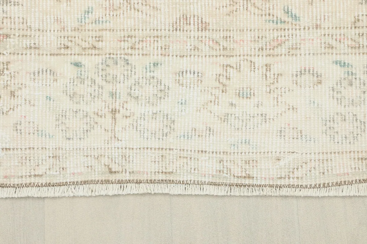 Close-up of the rug's border and fringe, showcasing the intricate patterns and natural wear