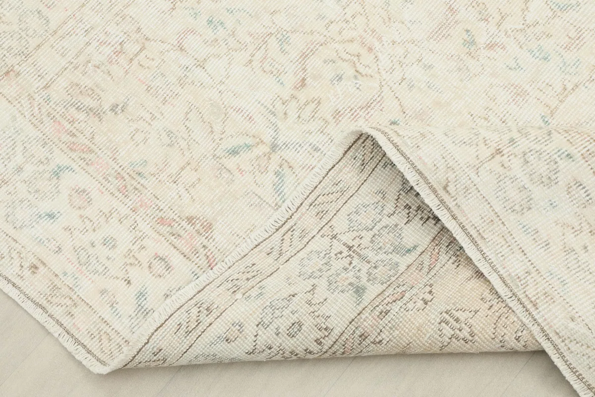 Corner of the rug folded back, showing the cotton foundation and the reverse side of the weave