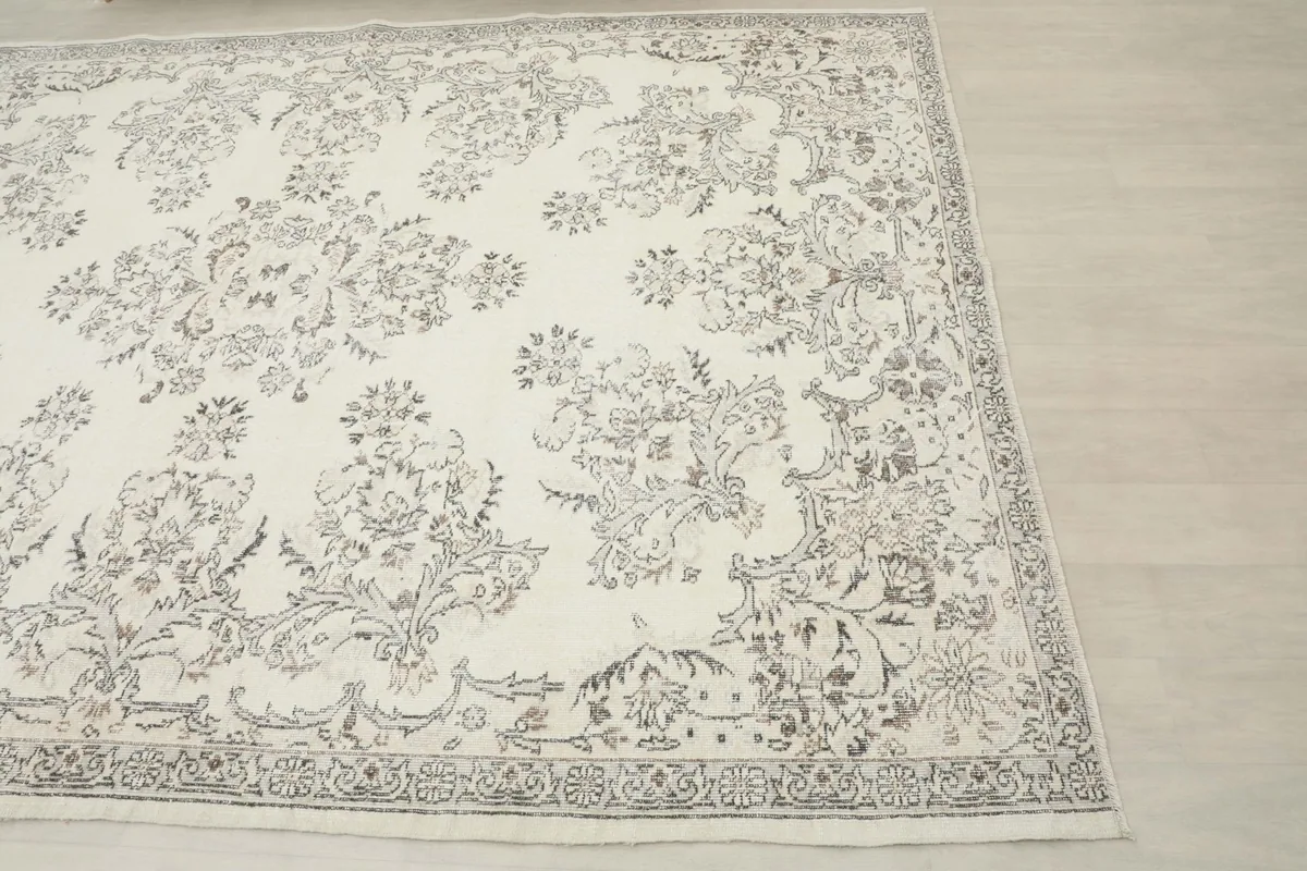Corner view of the vintage Anatolian rug, showing the intricate gray floral border and part of the main field.