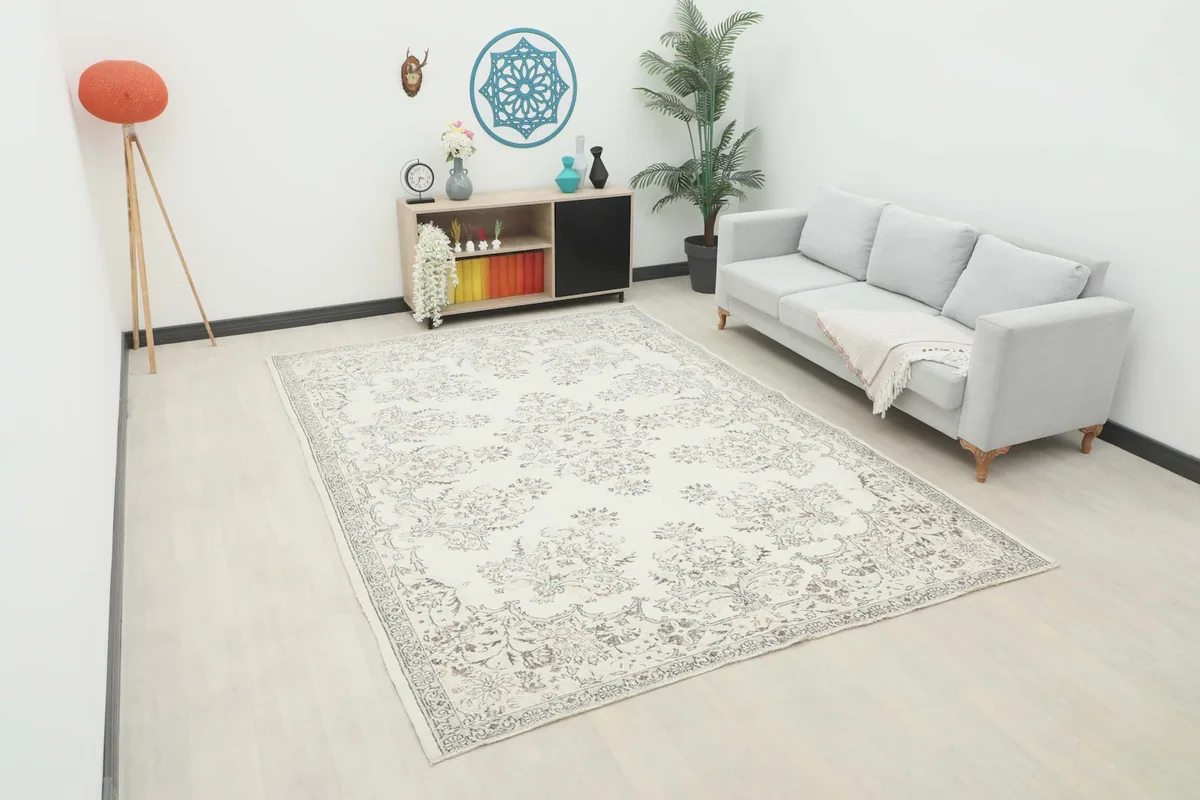 Ivory and gray vintage Anatolian rug displayed in a bright living room setting with a light gray sofa and wooden cabinet.